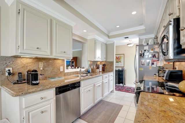 kitchen with sink, crown molding, a tray ceiling, stainless steel appliances, and light stone countertops