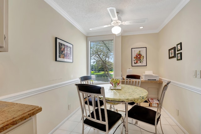 tiled dining area with ceiling fan, ornamental molding, and a textured ceiling