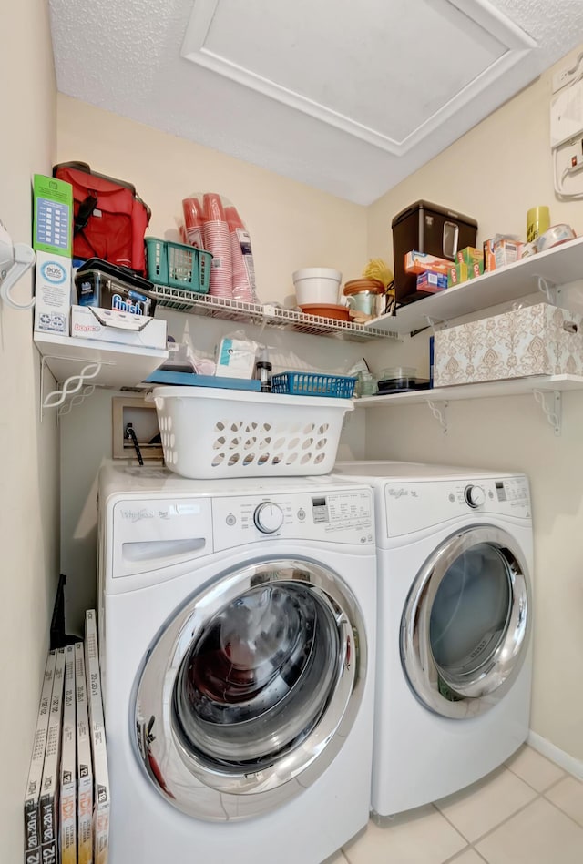 clothes washing area with light tile patterned floors, washing machine and clothes dryer, and a textured ceiling