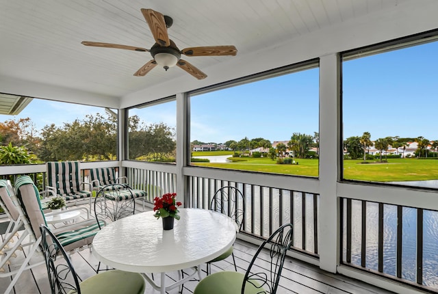 sunroom / solarium featuring ceiling fan and a water view