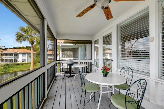 sunroom featuring a water view and ceiling fan