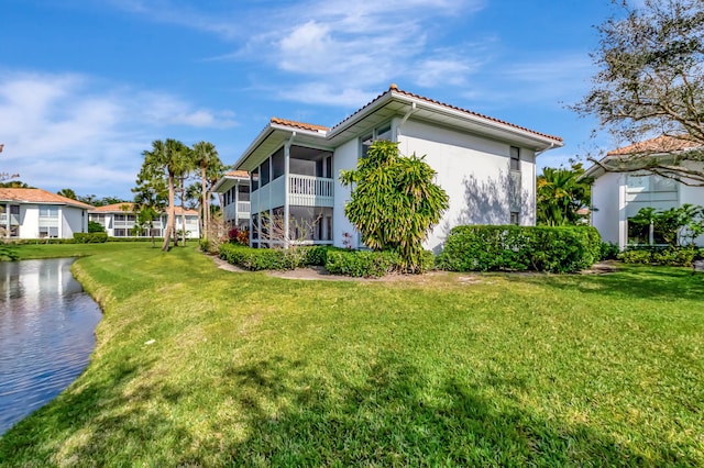 view of side of property with a water view, a yard, and a sunroom