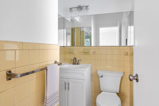 bathroom with vanity, toilet, and tile walls