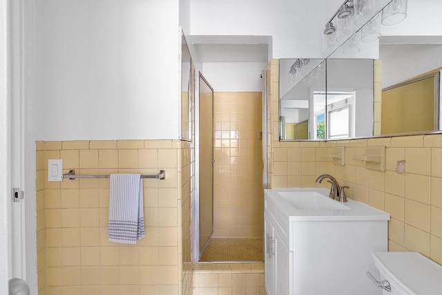 bathroom featuring tiled shower, vanity, toilet, and tile walls