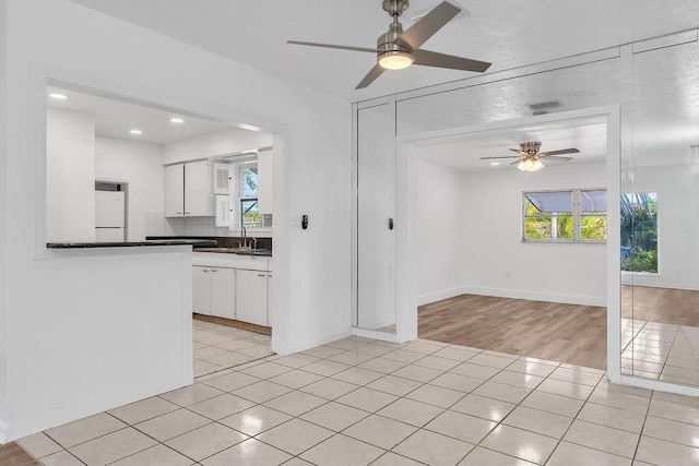 kitchen with light tile patterned floors, sink, refrigerator, white cabinetry, and backsplash