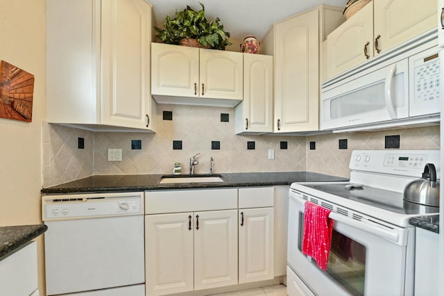 kitchen featuring tasteful backsplash, white appliances, dark stone counters, and sink