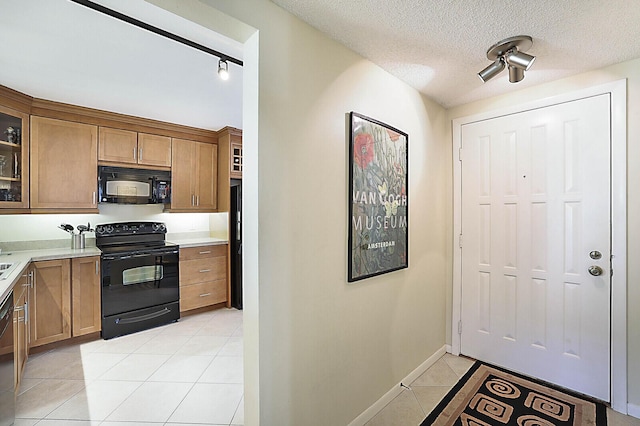 kitchen with light tile patterned floors, track lighting, black appliances, and a textured ceiling