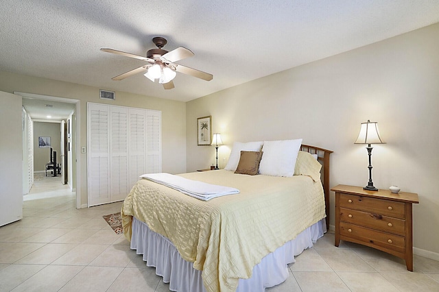 tiled bedroom featuring ceiling fan, a closet, and a textured ceiling