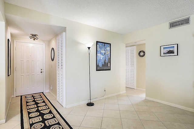 corridor with light tile patterned floors and a textured ceiling