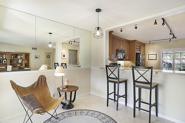 kitchen featuring decorative light fixtures, light tile patterned floors, a textured ceiling, and black appliances