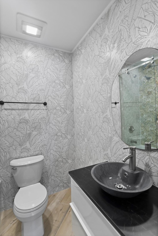 bathroom with vanity, a shower with shower door, hardwood / wood-style floors, and toilet