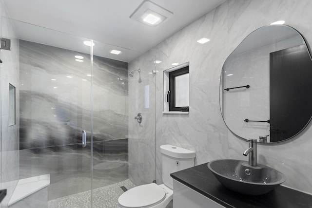 bathroom with tile walls, an enclosed shower, vanity, and toilet