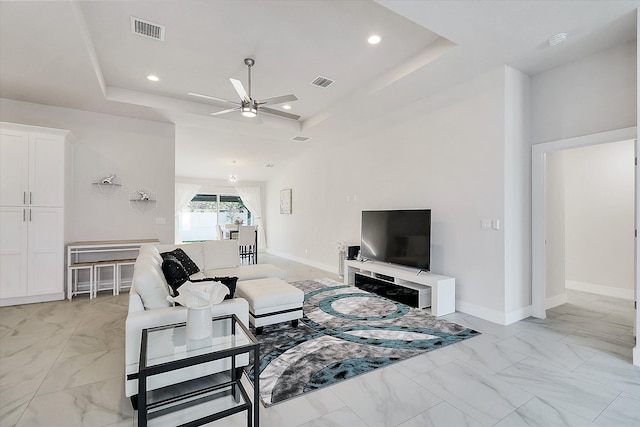 living room featuring a raised ceiling and ceiling fan