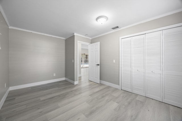 unfurnished bedroom with ornamental molding, a closet, and light wood-type flooring