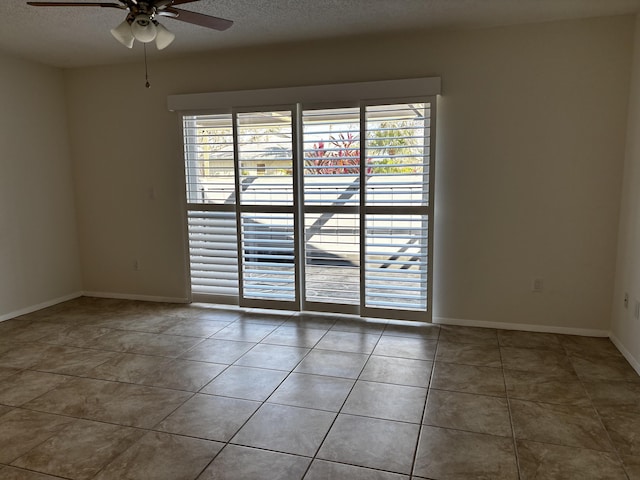 empty room with ceiling fan, tile patterned floors, and a textured ceiling