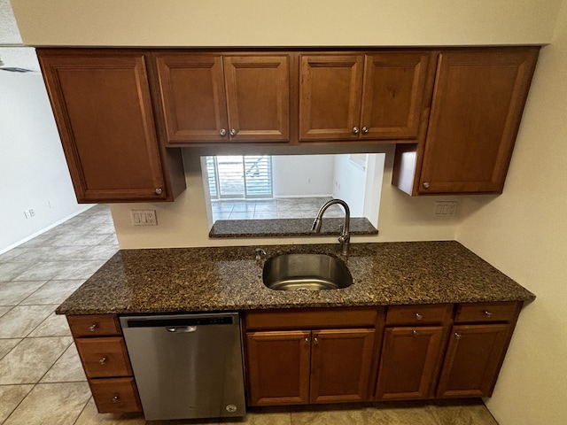 kitchen with dark stone counters, stainless steel dishwasher, and a sink