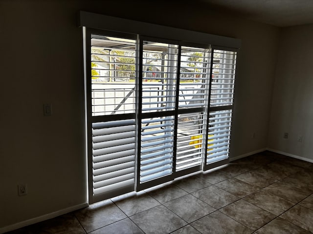 interior space featuring baseboards, tile patterned floors, and a healthy amount of sunlight