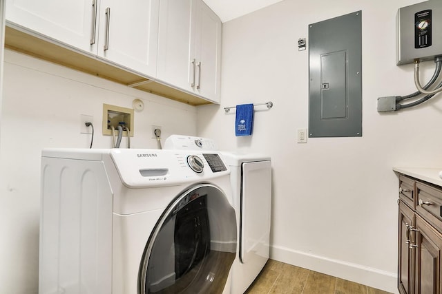 washroom featuring cabinets, light wood-type flooring, electric panel, and independent washer and dryer