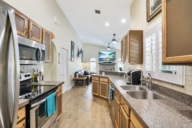 kitchen with sink, vaulted ceiling, stainless steel appliances, light hardwood / wood-style floors, and decorative backsplash