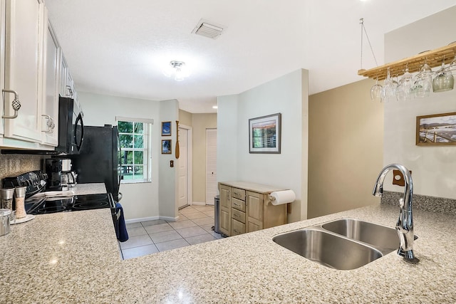 kitchen with sink, light tile patterned floors, kitchen peninsula, and black appliances