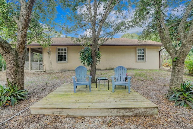 rear view of house featuring a wooden deck and a sunroom