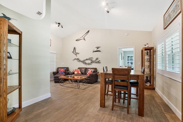 dining area with rail lighting, high vaulted ceiling, and dark hardwood / wood-style floors