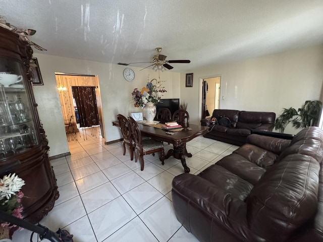 living room featuring ceiling fan, light tile patterned floors, and a textured ceiling