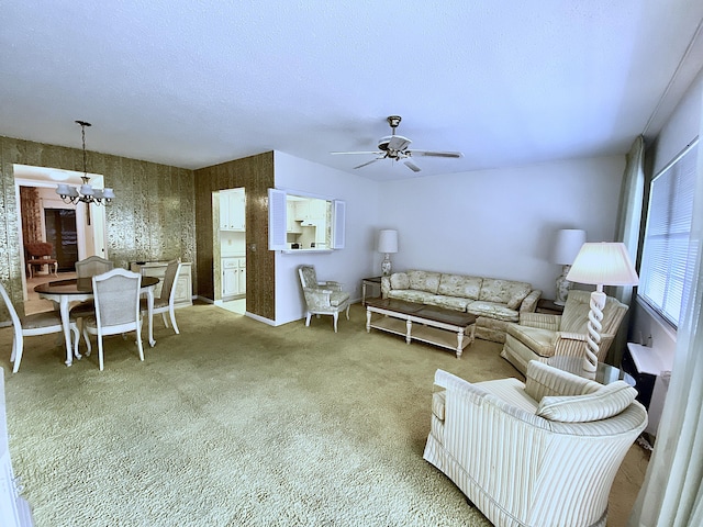 carpeted living room featuring ceiling fan with notable chandelier