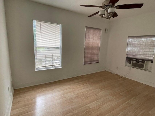 spare room with cooling unit, ceiling fan, and light wood-type flooring