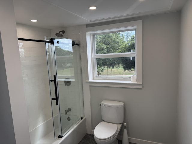 bathroom with toilet and combined bath / shower with glass door