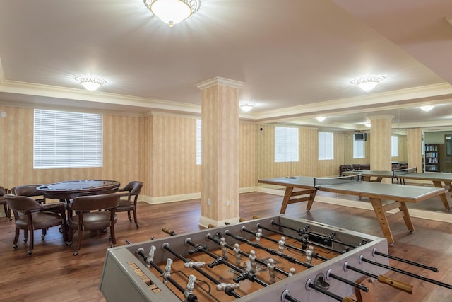 recreation room featuring decorative columns, ornamental molding, a raised ceiling, and dark hardwood / wood-style floors