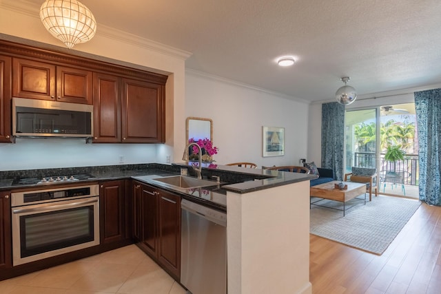 kitchen featuring appliances with stainless steel finishes, decorative light fixtures, kitchen peninsula, and sink