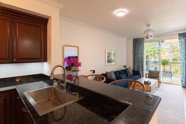 kitchen featuring sink, crown molding, and dark stone counters