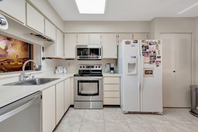 kitchen featuring stainless steel appliances, light tile patterned flooring, sink, and white cabinets