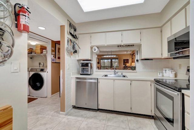 kitchen featuring sink, white cabinetry, light tile patterned floors, appliances with stainless steel finishes, and washer / clothes dryer