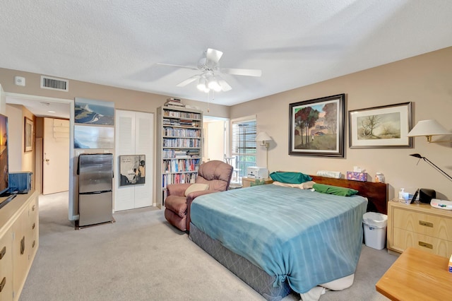 carpeted bedroom featuring ceiling fan, a textured ceiling, stainless steel refrigerator, and a closet