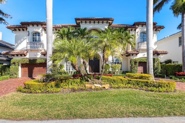 mediterranean / spanish house featuring a garage and a front lawn