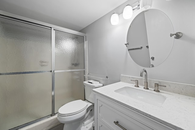 bathroom featuring a shower with door, vanity, and toilet