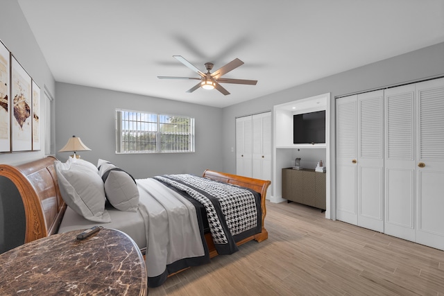 bedroom featuring two closets, light hardwood / wood-style floors, and ceiling fan