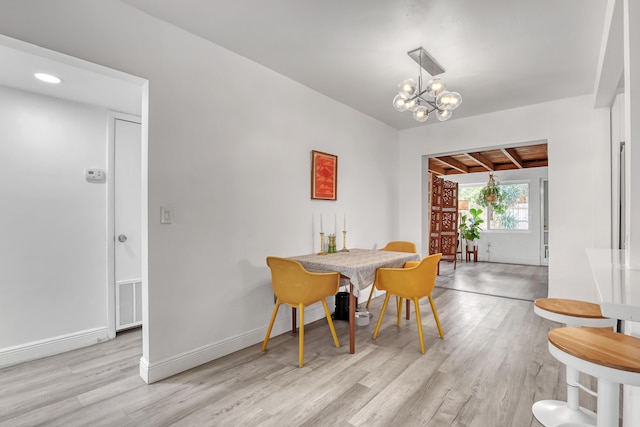 dining room featuring beamed ceiling, an inviting chandelier, and light wood-type flooring