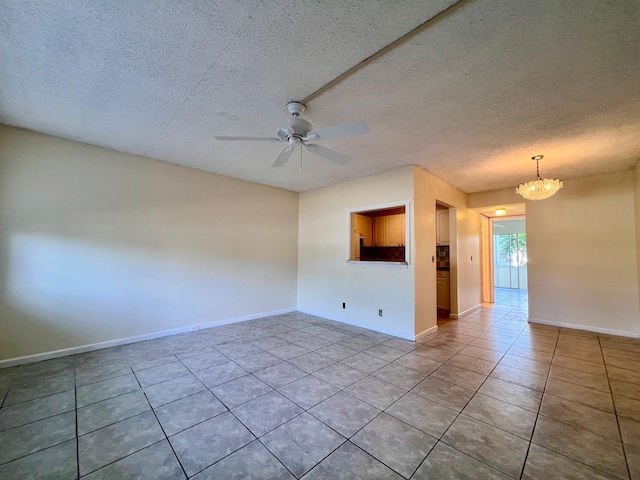 tiled spare room with ceiling fan with notable chandelier and a textured ceiling