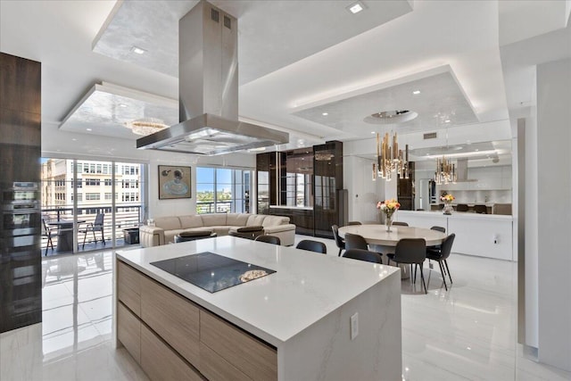 kitchen featuring a spacious island, a tray ceiling, pendant lighting, island exhaust hood, and black electric stovetop