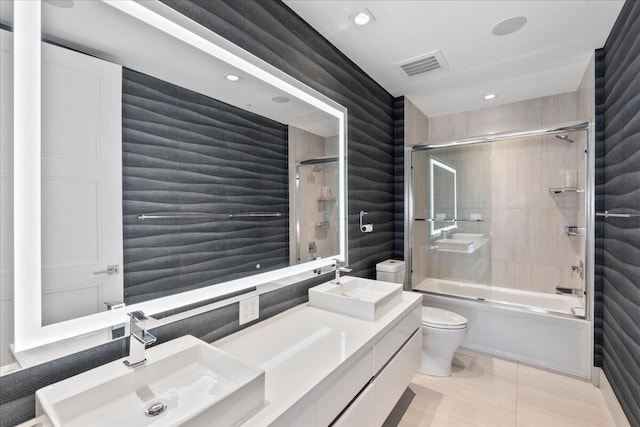 full bathroom with tile patterned flooring, tiled shower / bath, vanity, and toilet