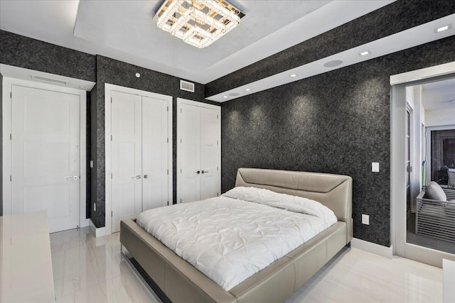 bedroom featuring multiple closets and a tray ceiling