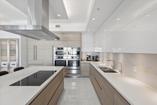 kitchen with black electric cooktop, island range hood, decorative backsplash, and stainless steel double oven