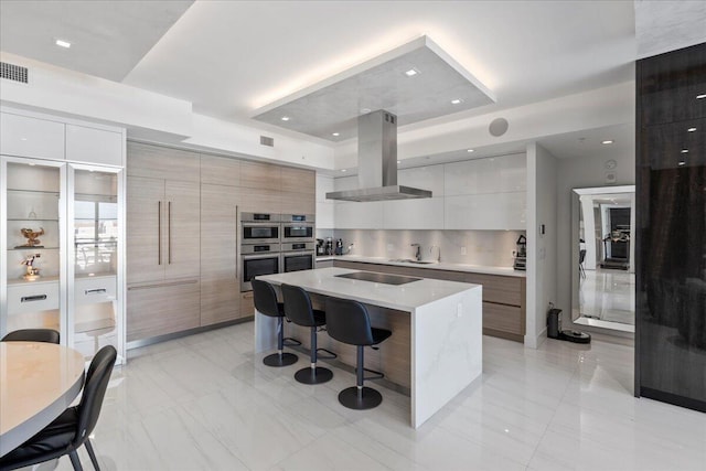 kitchen featuring island range hood, white cabinets, a kitchen breakfast bar, black electric stovetop, and a spacious island