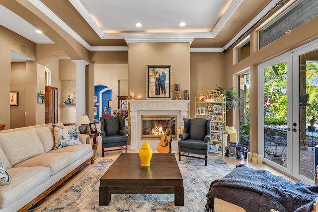 living room featuring crown molding, a tray ceiling, french doors, and ornate columns