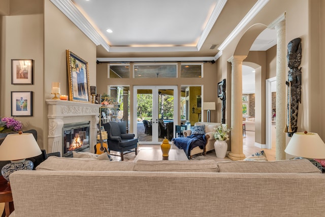 interior space featuring french doors, crown molding, a tray ceiling, decorative columns, and a high ceiling