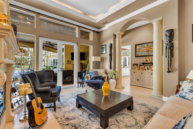 living room featuring light tile patterned floors, crown molding, a raised ceiling, and ornate columns