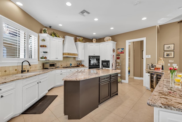 kitchen with light stone counters, sink, custom exhaust hood, and wine cooler